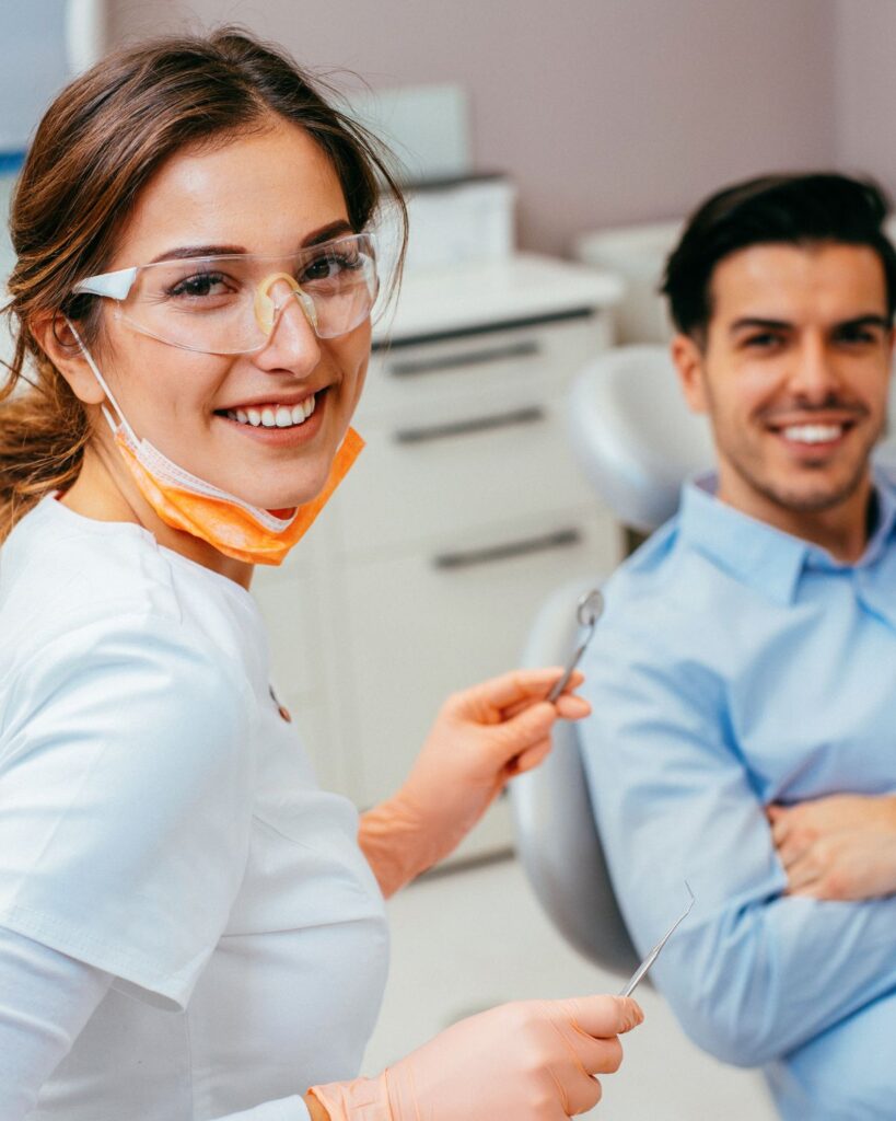 A dentist is smiling while holding a dental tool